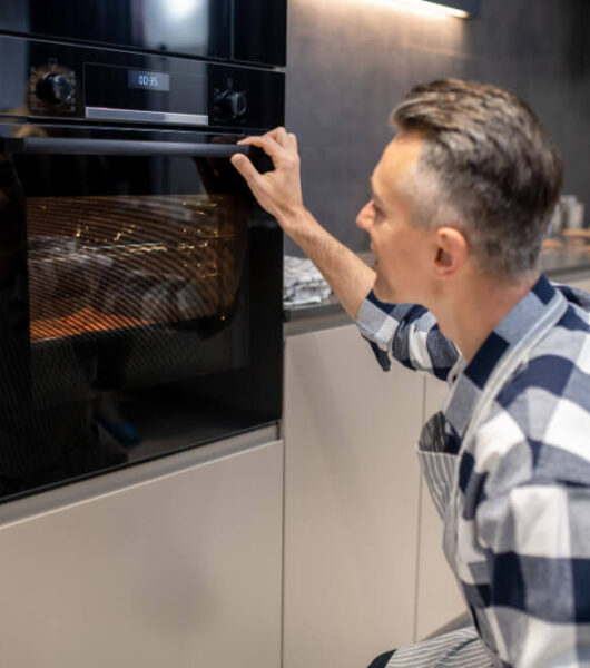 man-crouched-watching-baking-electric-oven (1)