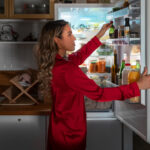 woman in a red dress looking into a refrigerator