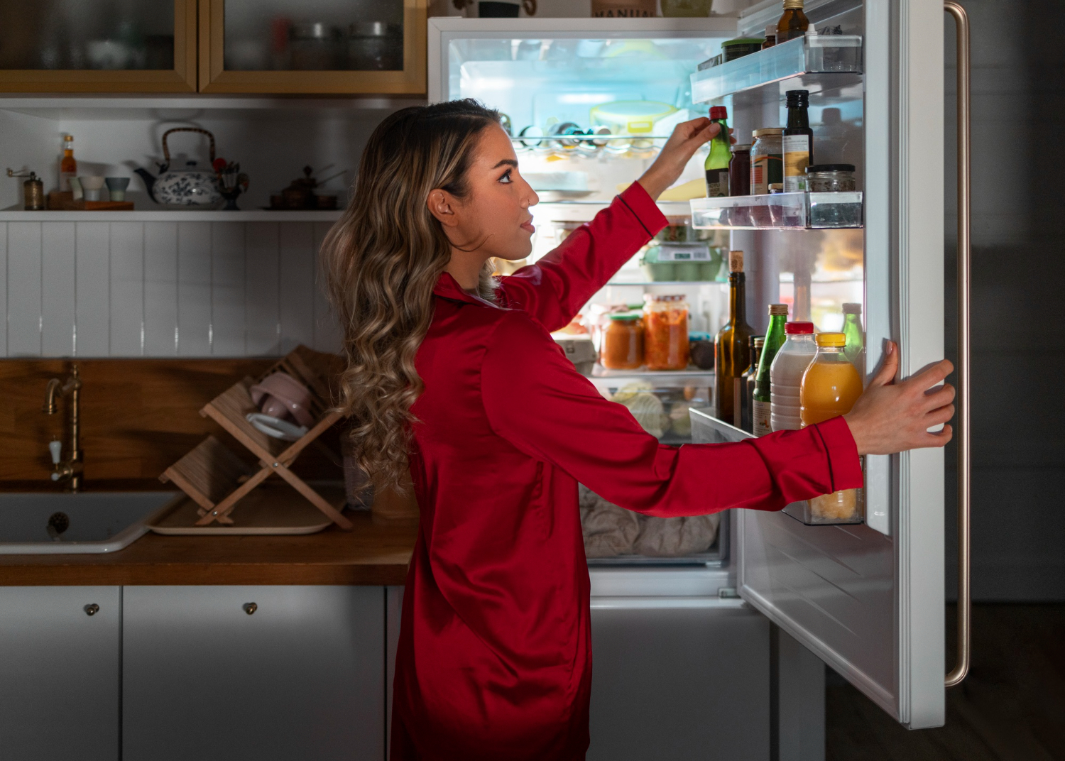 woman in a red dress looking into a refrigerator